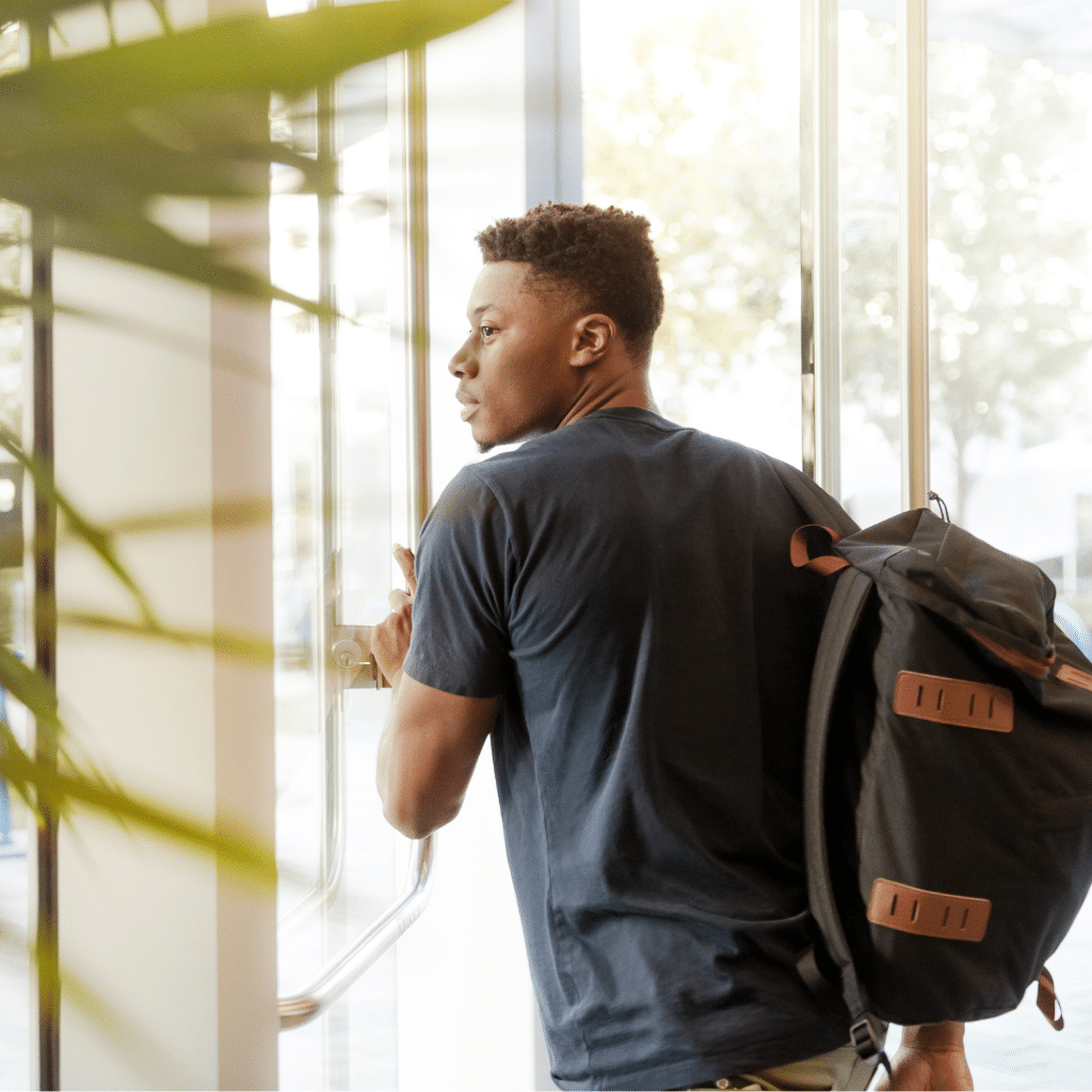 jeune homme avec un sac à dos devant une porte