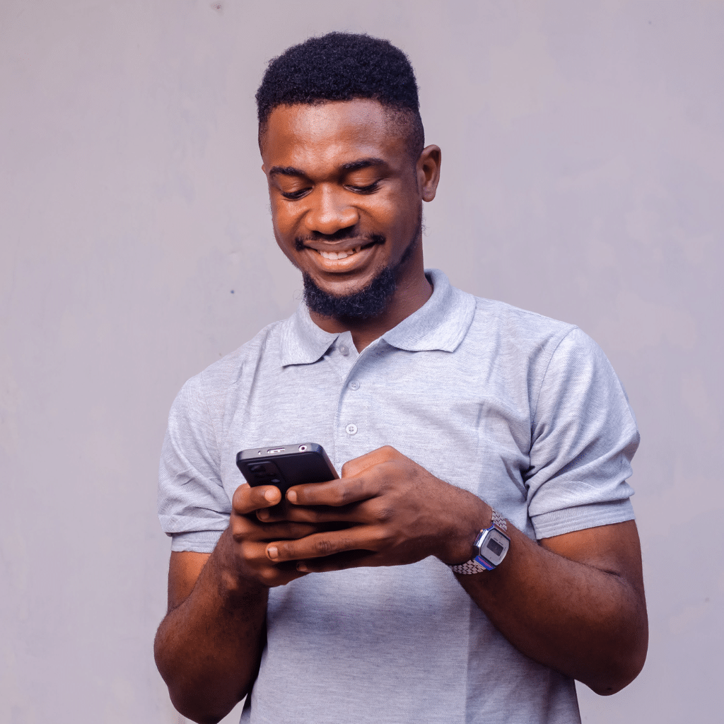 homme souriant devant son téléphone portable